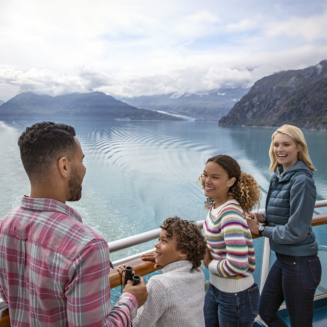 Family looking out over railing at glaciers in Alaska.Click to book 7-day voyage of the glaciers from vancouver cruise.