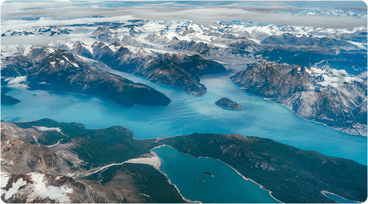 Arial view of Alaska mountains and blue water inlets.