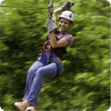 Girl ziplining above rainforest.